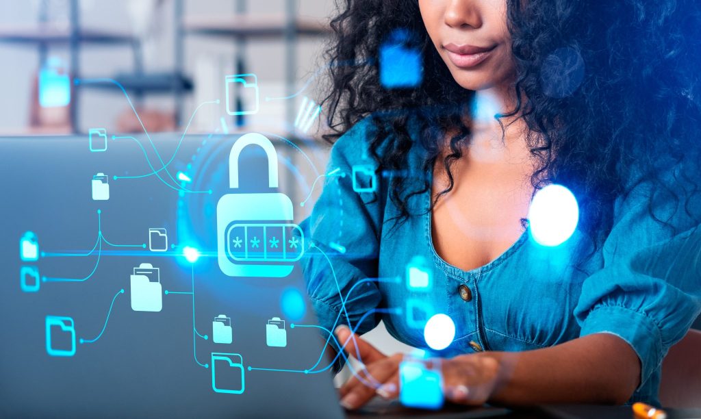 Woman working on a laptop with a glowing padlock and folder-network overlay symbolising data security.